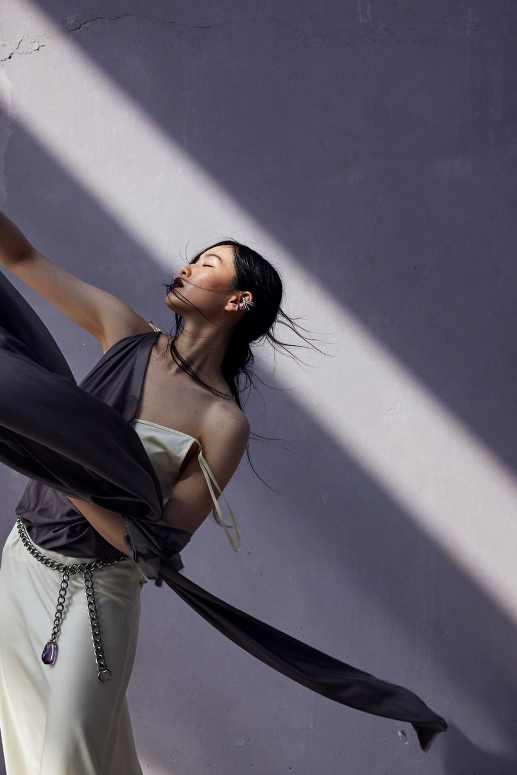 Dark silk caught mid-movement against a raw plaster wall under a hard diagonal of light - rendered by McLeuker AI